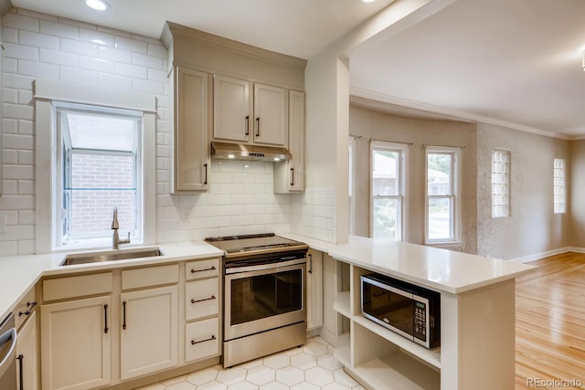 kitchen with kitchen peninsula, tasteful backsplash, stainless steel appliances, sink, and cream cabinets