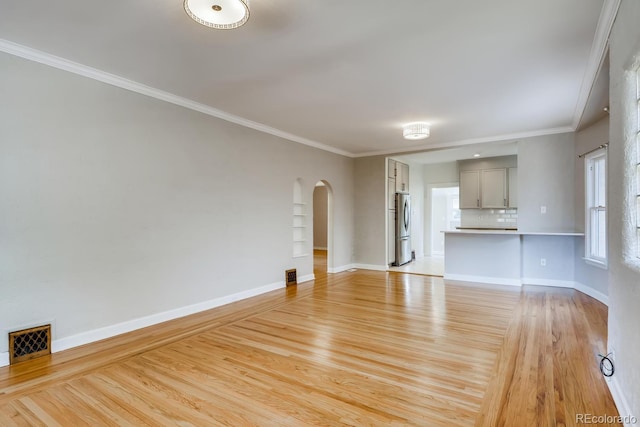 unfurnished living room featuring crown molding and light wood-type flooring