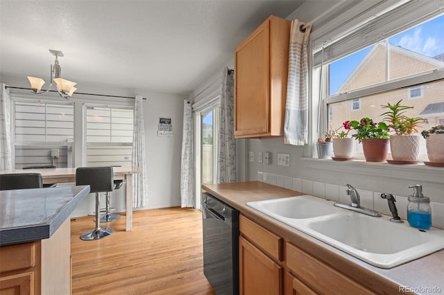9272 E 108th Ave, Commerce City, CO 80640 - kitchen featuring black dishwasher, light wood-style flooring, a chandelier, and decorative light fixtures