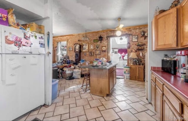 kitchen featuring ceiling fan, a kitchen bar, white fridge, and brick wall