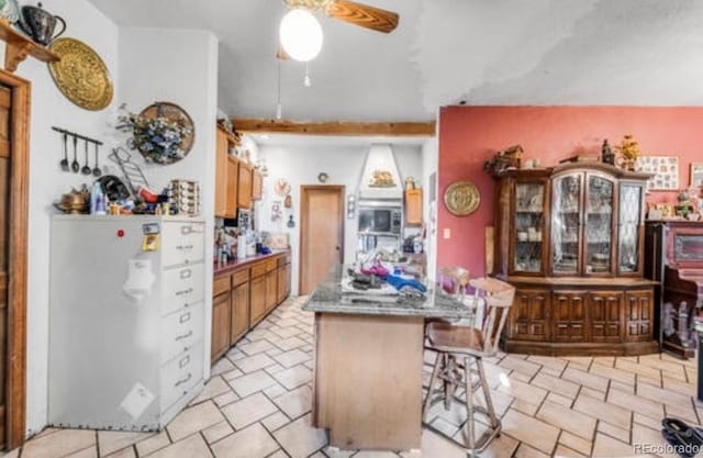 kitchen featuring ceiling fan, a breakfast bar, and refrigerator