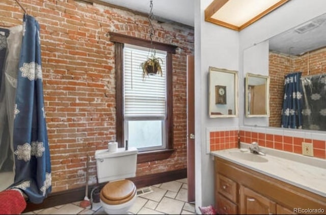 bathroom with vanity, brick wall, toilet, and tasteful backsplash