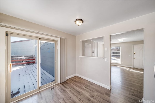 empty room featuring wood finished floors, visible vents, and baseboards