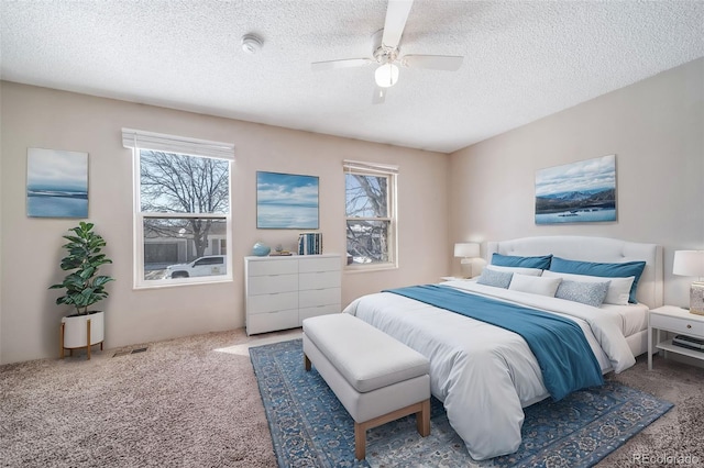 bedroom with a textured ceiling, carpet floors, visible vents, and a ceiling fan