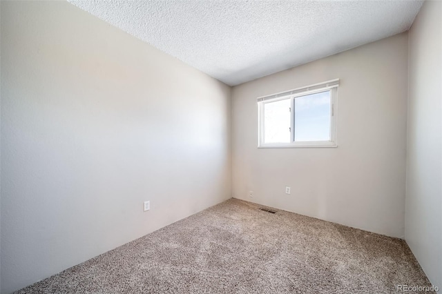 carpeted empty room featuring visible vents and a textured ceiling