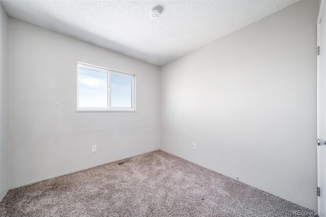 empty room featuring visible vents, a textured ceiling, and carpet flooring