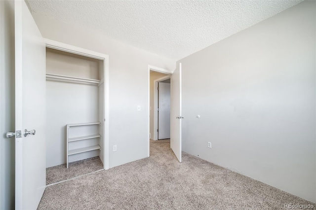 unfurnished bedroom with a textured ceiling, a closet, and light colored carpet