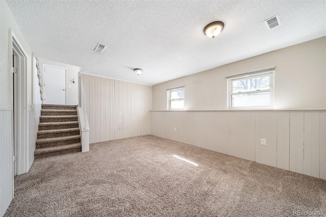 basement featuring carpet, wainscoting, visible vents, and stairs