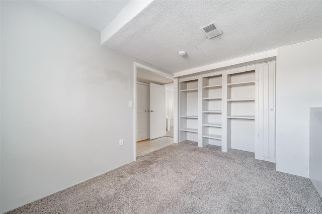 unfurnished bedroom with light carpet, visible vents, and a textured ceiling