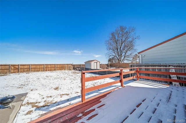 yard layered in snow with a storage shed, a fenced backyard, and an outdoor structure