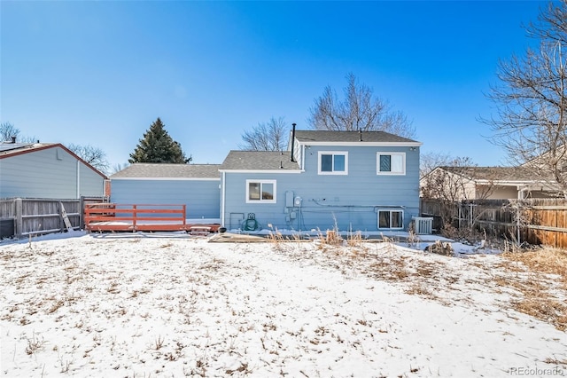 snow covered back of property with cooling unit and a fenced backyard