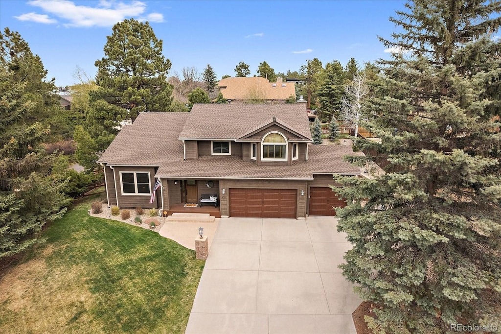 view of front facade featuring a shingled roof, a garage, concrete driveway, and a front yard