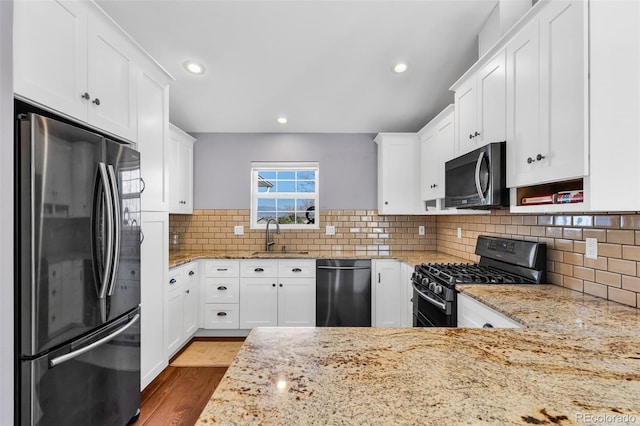 kitchen featuring sink, white cabinets, light stone counters, and black appliances