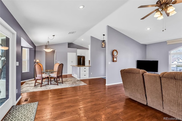 living room with dark wood-type flooring, ceiling fan, and vaulted ceiling