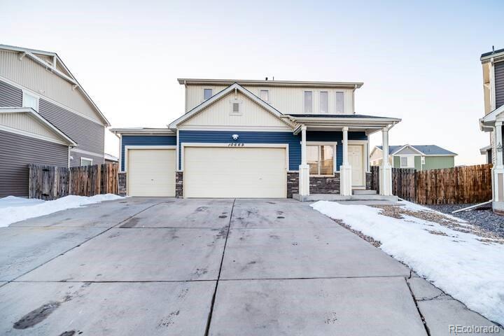 10669 Worchester Dr, Commerce City, CO 80022 - view of front of house with concrete driveway, an attached garage, stone siding, and a porch