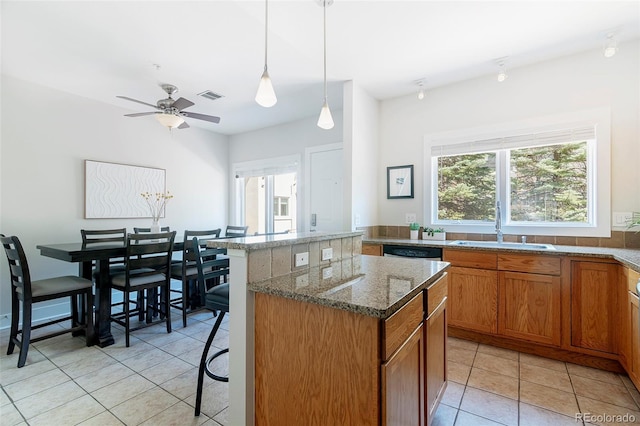 2800 Aurora Ave Unit 121, Boulder, CO 80303 - kitchen featuring a kitchen island, light tile patterned flooring, brown cabinetry, stone counters, and dishwasher