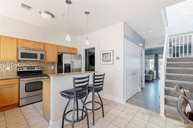 2800 Aurora Ave Unit 121, Boulder, CO 80303 - kitchen with appliances with stainless steel finishes, light tile patterned flooring, tasteful backsplash, a center island, and a breakfast bar area