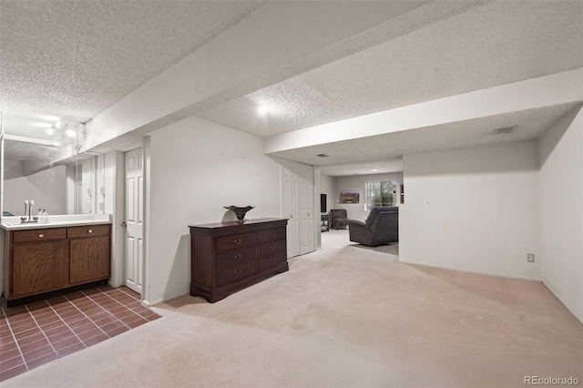 interior space with a textured ceiling, visible vents, a sink, baseboards, and carpet flooring