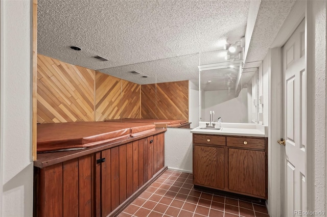 bathroom with wooden walls, visible vents, tile patterned flooring, and vanity