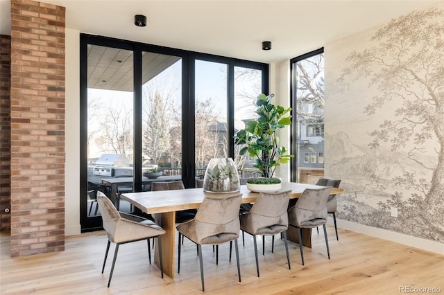 dining space featuring light wood-type flooring and a wall of windows