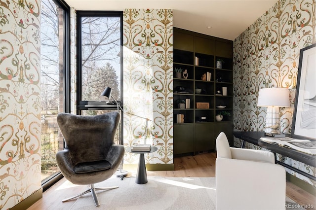 sitting room with light wood-type flooring, floor to ceiling windows, and a healthy amount of sunlight