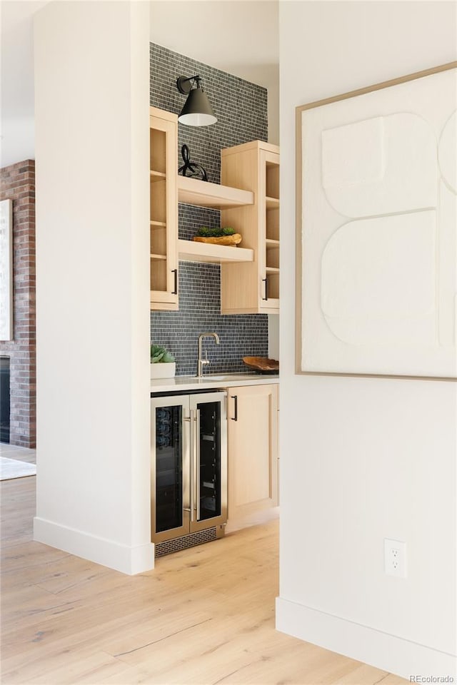 bar with decorative backsplash, light brown cabinetry, wine cooler, and light hardwood / wood-style flooring