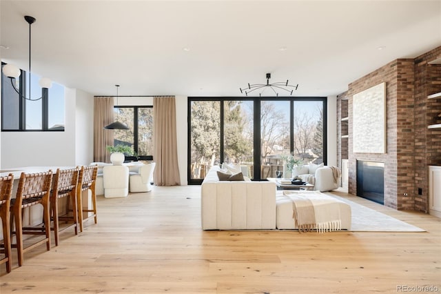 living room featuring floor to ceiling windows, light wood-type flooring, and a brick fireplace