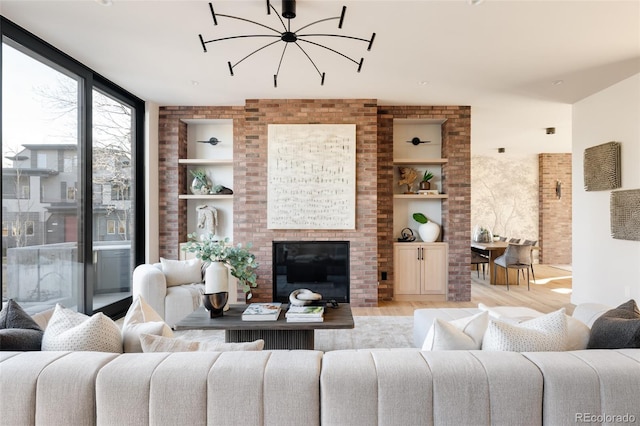 living room with built in shelves, a notable chandelier, and light wood-type flooring