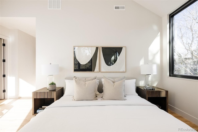 bedroom with light wood-type flooring and vaulted ceiling