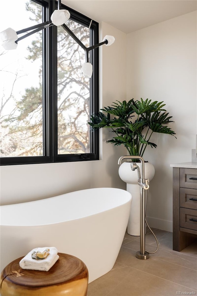 bathroom featuring tile patterned flooring, a tub to relax in, and a healthy amount of sunlight