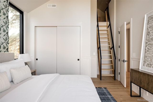 bedroom with light wood-type flooring, a closet, and lofted ceiling