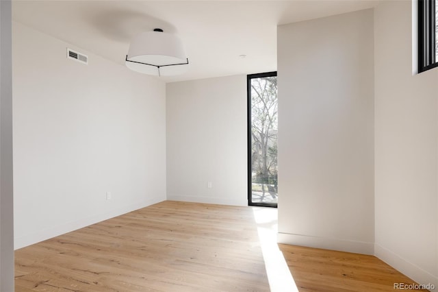 unfurnished room with floor to ceiling windows, a healthy amount of sunlight, and light wood-type flooring