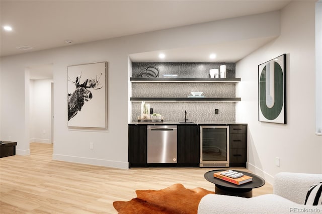 bar with sink, tasteful backsplash, wine cooler, stainless steel dishwasher, and light hardwood / wood-style floors