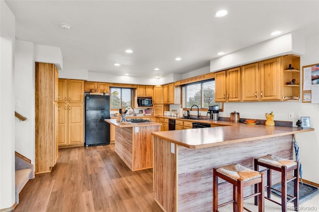 90 Riggs Rd, Westcliffe, CO 81252 - kitchen featuring black appliances, a kitchen island, a kitchen bar, light wood-style flooring, and recessed lighting