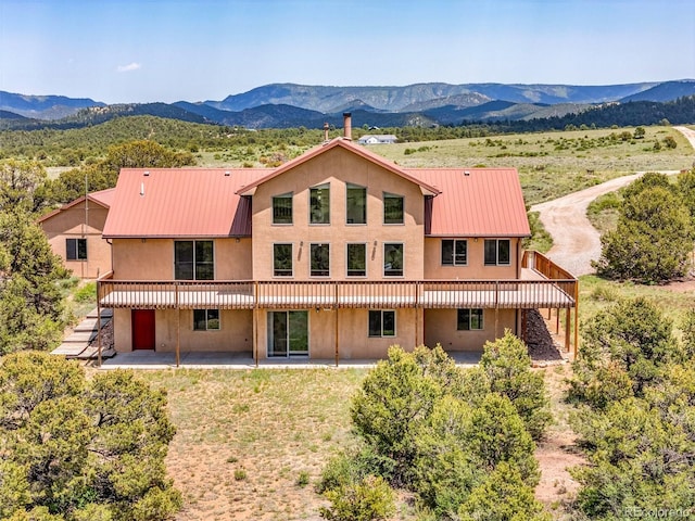 90 Riggs Rd, Westcliffe, CO 81252 - back of property featuring a mountain view, a patio area, stucco siding, and a metal roof