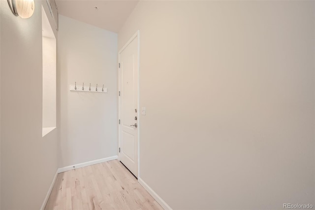 hall featuring light wood finished floors and baseboards