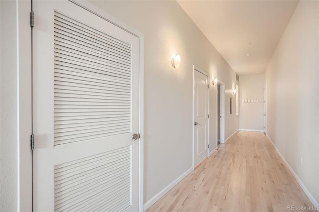 corridor with light wood-style floors and baseboards