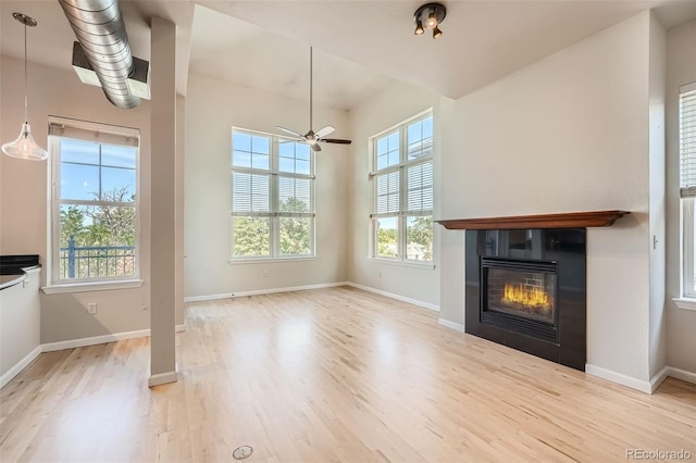 unfurnished living room featuring light wood finished floors, baseboards, and a tile fireplace