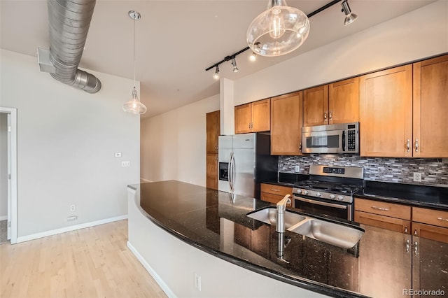 kitchen with stainless steel appliances, track lighting, brown cabinets, and backsplash