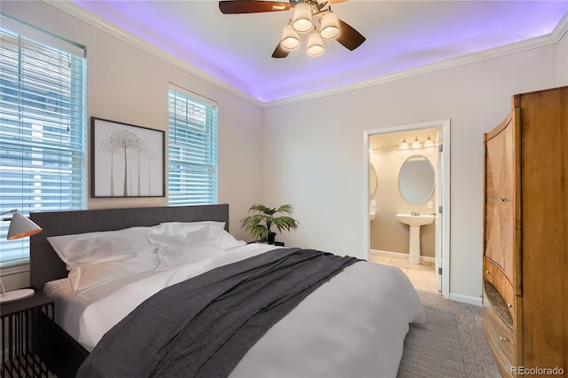 bedroom featuring light carpet, baseboards, a ceiling fan, ensuite bath, and crown molding