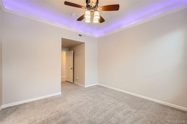 spare room featuring ceiling fan, light carpet, visible vents, baseboards, and crown molding