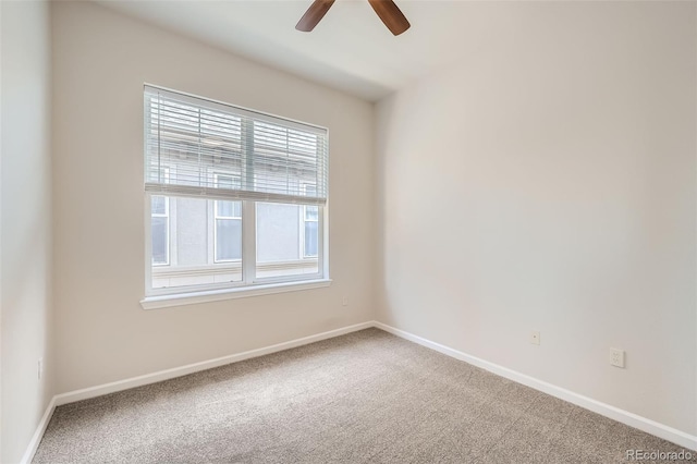 carpeted spare room with a wealth of natural light, ceiling fan, and baseboards