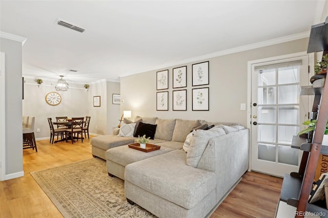 living area with light wood-type flooring, baseboards, visible vents, and ornamental molding