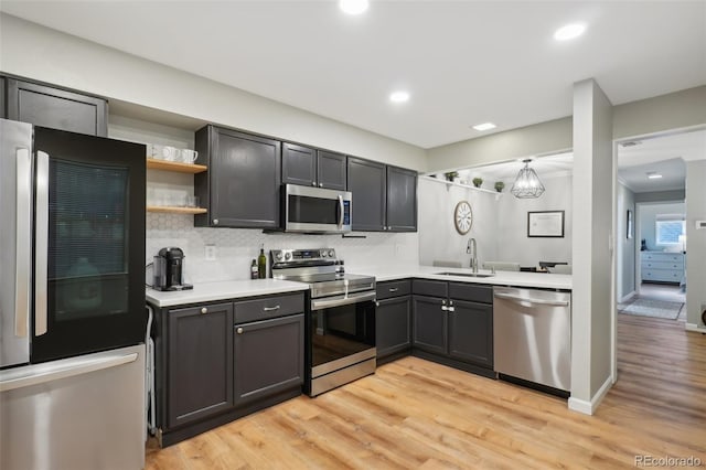 kitchen with backsplash, stainless steel appliances, light countertops, and a sink