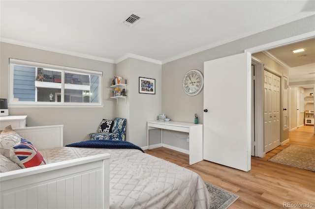 bedroom with visible vents, baseboards, wood finished floors, and crown molding