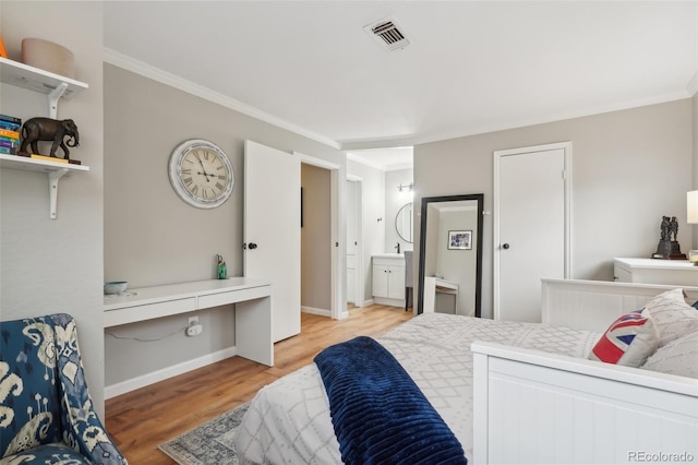 bedroom with visible vents, light wood-style flooring, ornamental molding, connected bathroom, and built in study area