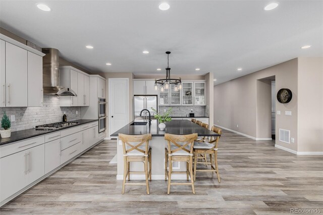 3059 Morningbird Ln, Castle Rock, CO 80109 - kitchen featuring wall chimney exhaust hood, stainless steel appliances, dark countertops, a sink, and a kitchen breakfast bar