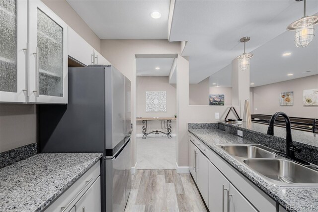 3059 Morningbird Ln, Castle Rock, CO 80109 - kitchen featuring a sink, light wood-style floors, freestanding refrigerator, white cabinetry, and pendant lighting