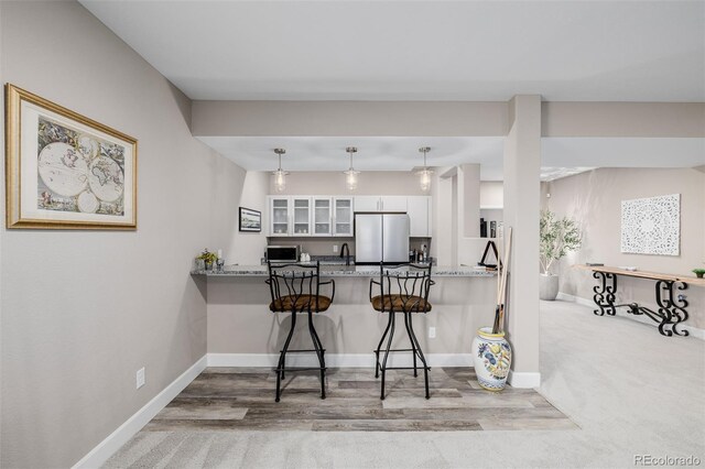 3059 Morningbird Ln, Castle Rock, CO 80109 - kitchen with appliances with stainless steel finishes, white cabinetry, a kitchen bar, glass insert cabinets, and a peninsula