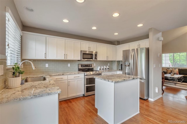 7472 S Memphis St, Aurora, CO 80016 - kitchen featuring appliances with stainless steel finishes, a sink, light wood-style flooring, white cabinetry, and decorative backsplash